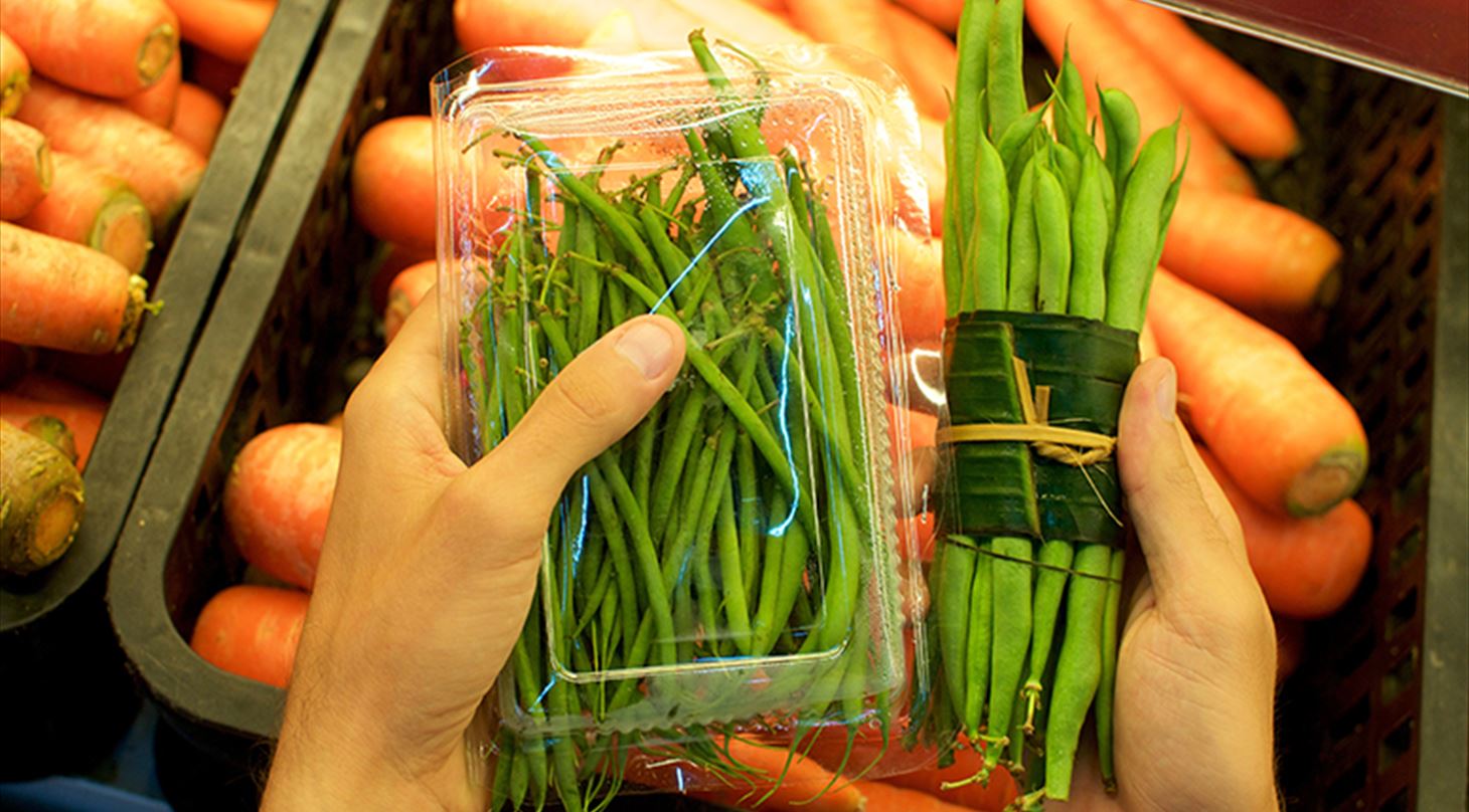 billedet viser bananblade brugt som emballage til grøntsager samt en almindelig plastemballage til samme grøntsag